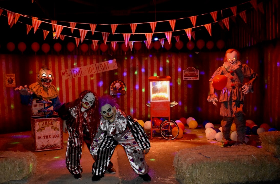 Two children in spooky Halloween costumes pose in a decorated room with orange and black banners.