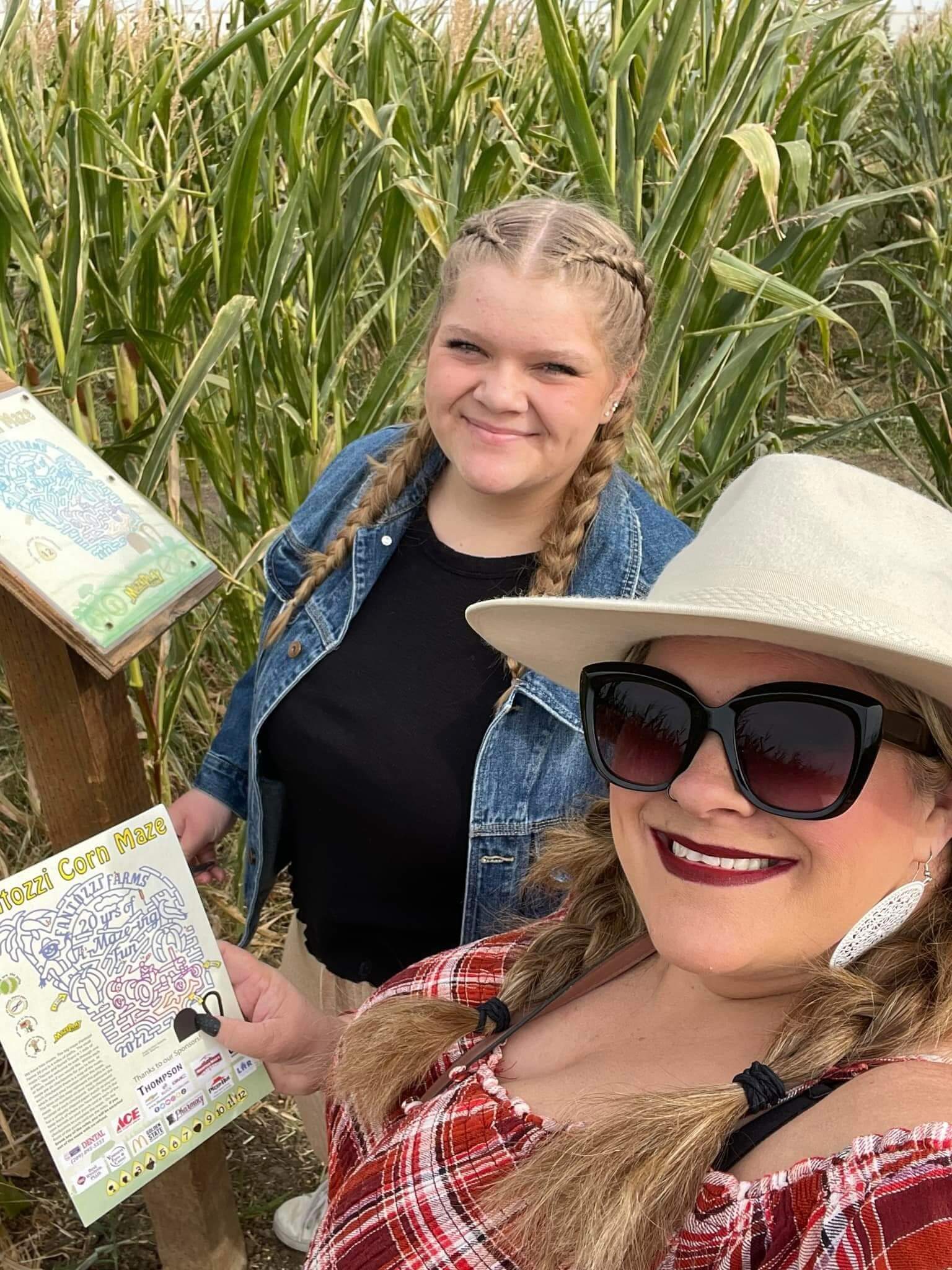 Two women holding pamphlets for a corn maze